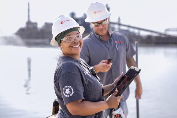 Two employees at the waterfront talking over a tablet device