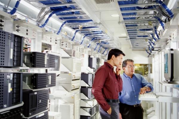 Zwei Arbeiter schauen auf einen Computer in einem Serverraum