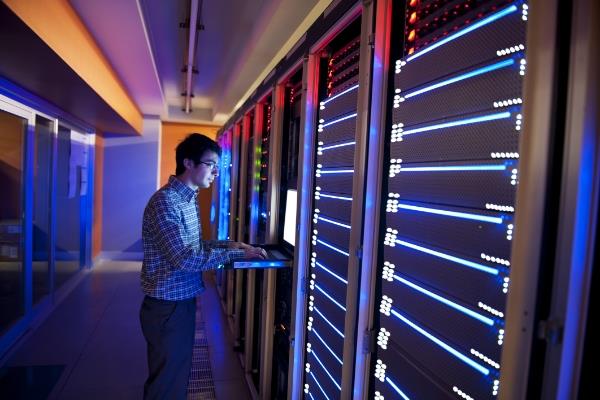 Mann betrachtet Serverregale und hält ein Klemmbrett