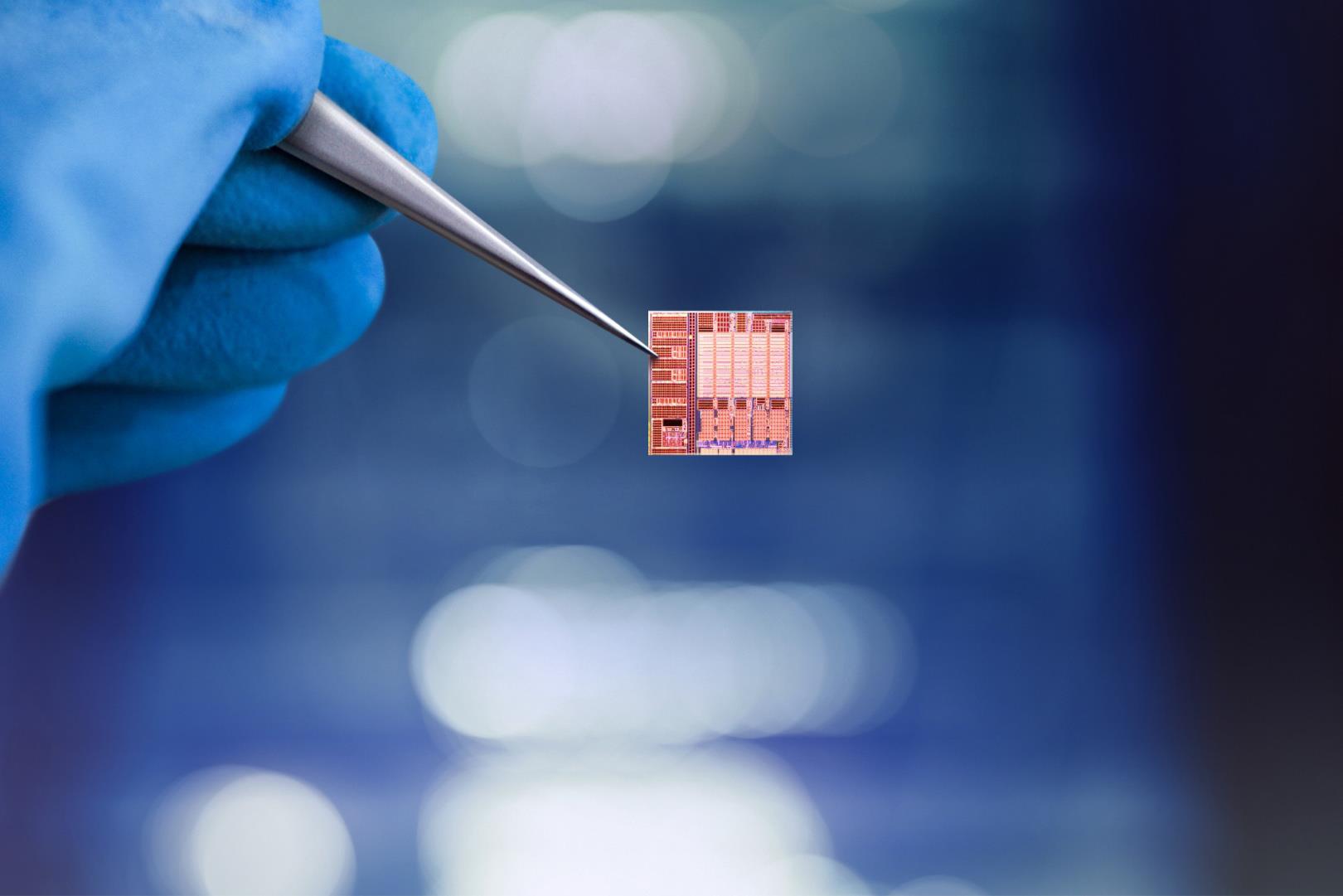 Hand mit Handschuh hält einen Mikrochip mit einer Pinzette.