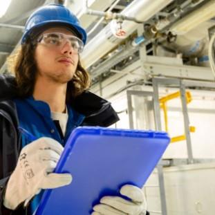 Student in hardhat taking notes on a clipboard