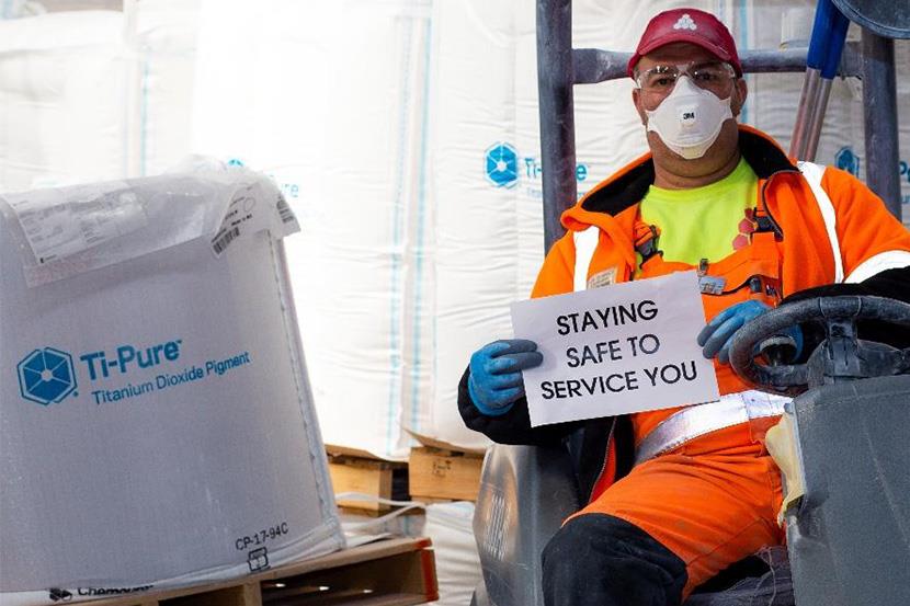 An image of a man in personal protective equipment holding a sign.