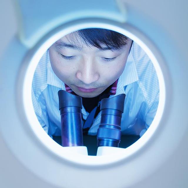 view through a round white opening person looking into microscope