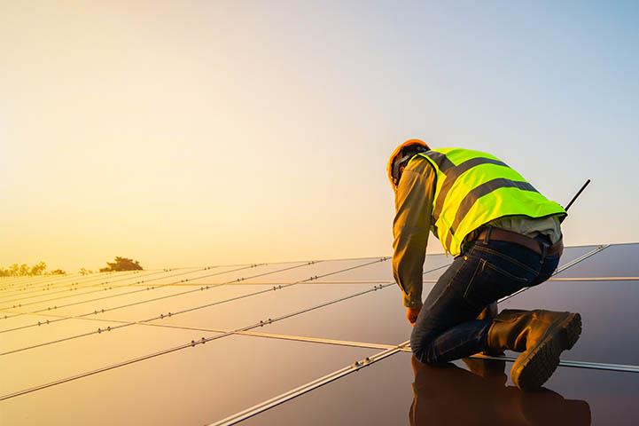Man kneeling on top of solar panels