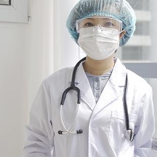 A woman in scrubs and PPE, standing in a hospital. 
