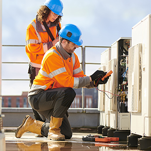 An image of two HVAC service technicians fixing an air conditioning system.