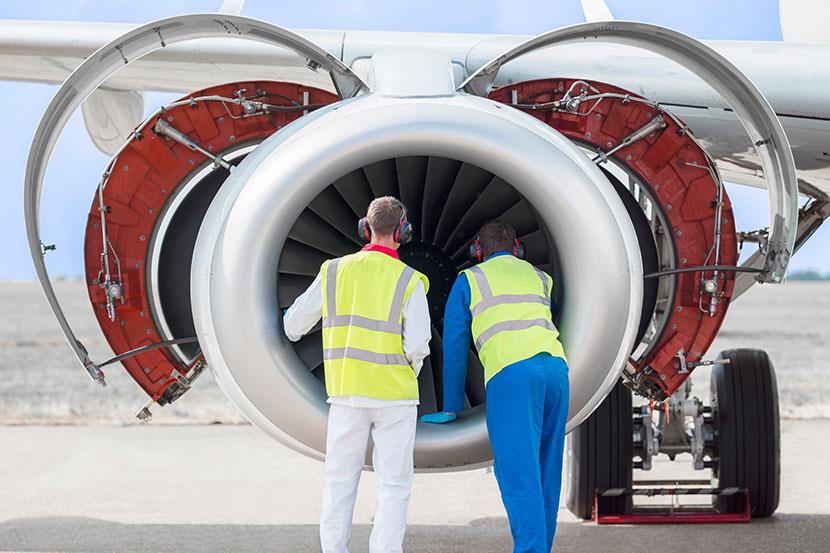 two men looking at airplane engine