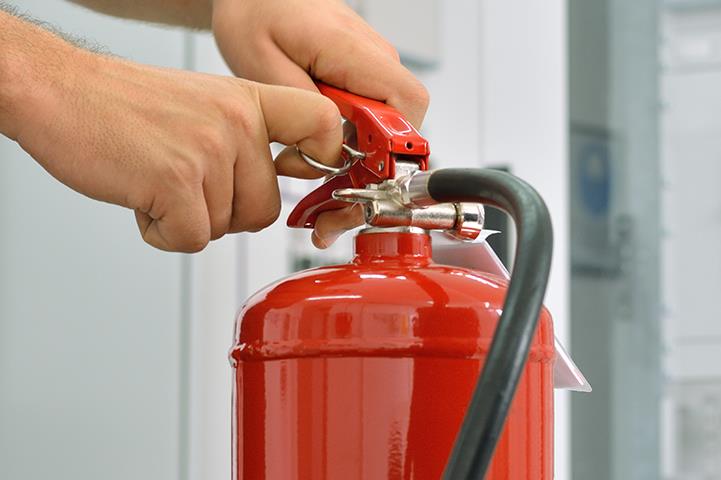 person removing pin from a red fire extinguisher