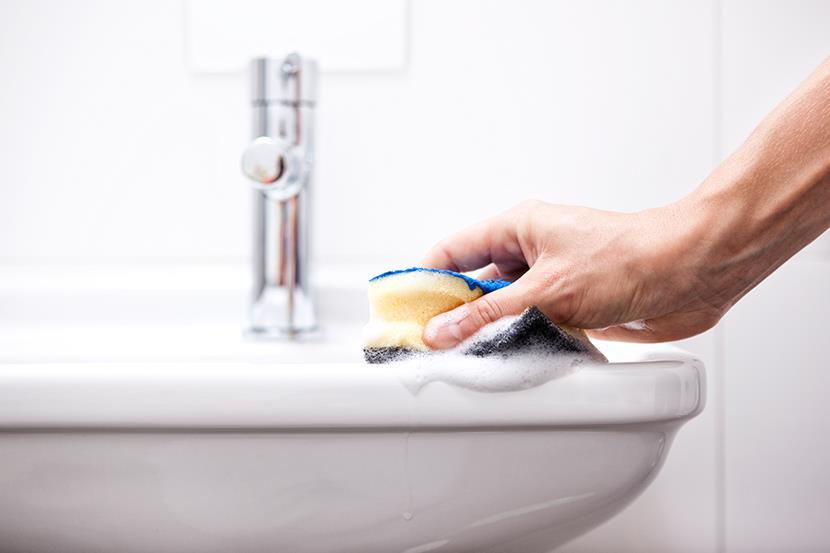 person using a sponge to clean a sink
