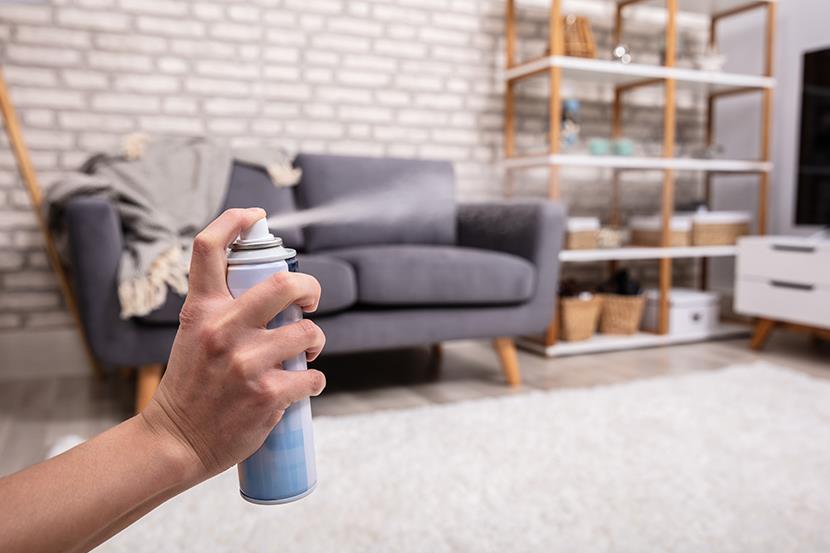 closeup of arm spraying air freshener in a living room 