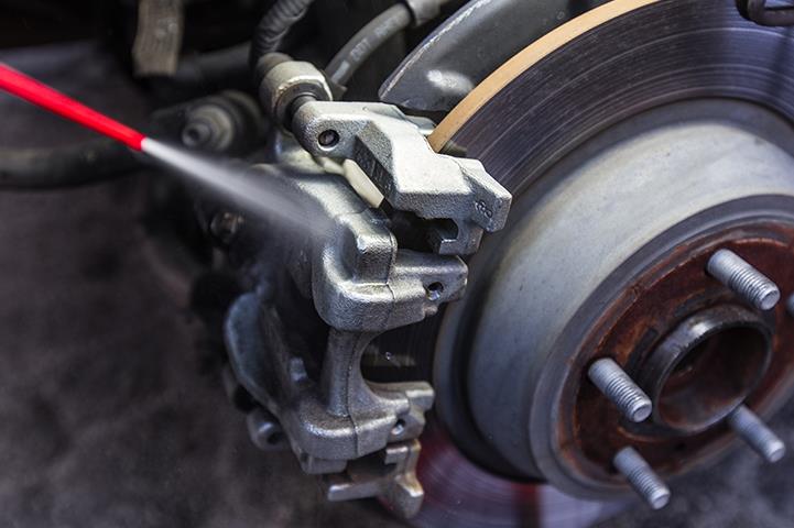 spraying car brake pad and disc with caliper 
