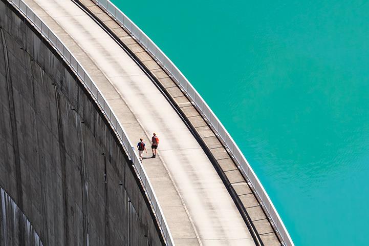 people walking on edge of hydrogen dam