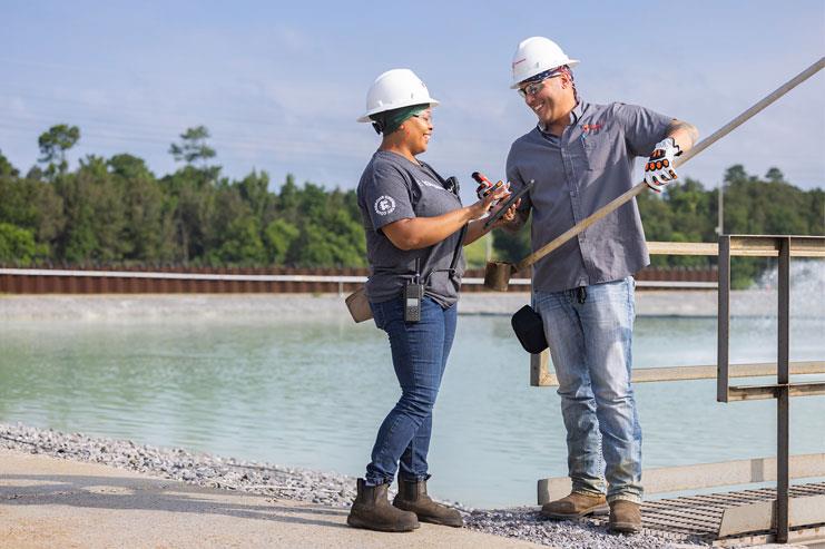 two employees at a worksite smiling