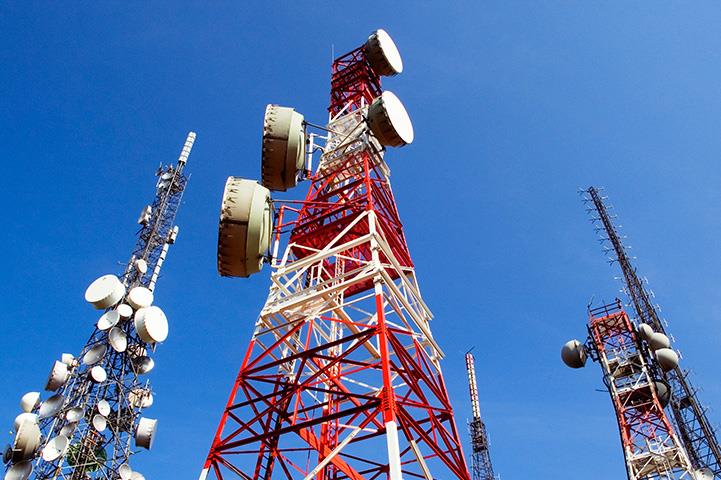 three telecommunications towers highlighted against a blue sky