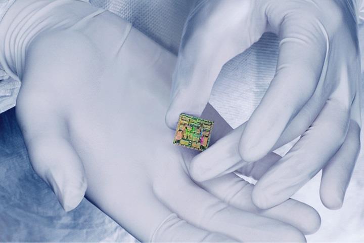 gloved hands holding a microchip